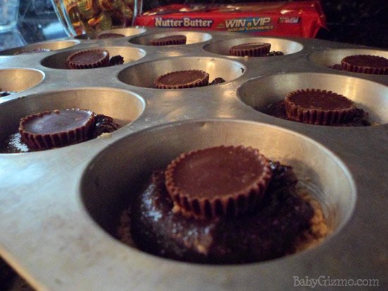 peanut butter cupcakes on top of brownie in a muffin pan