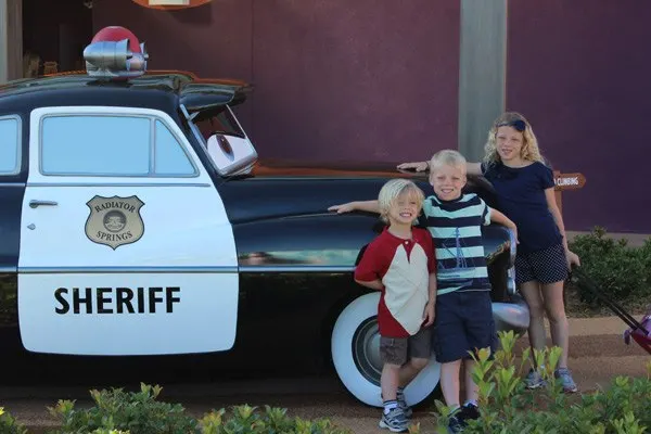 three kids in front of sheriff car in disney