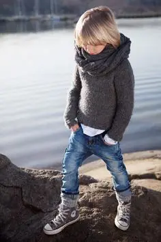 blonde boy standing on rocks by lake