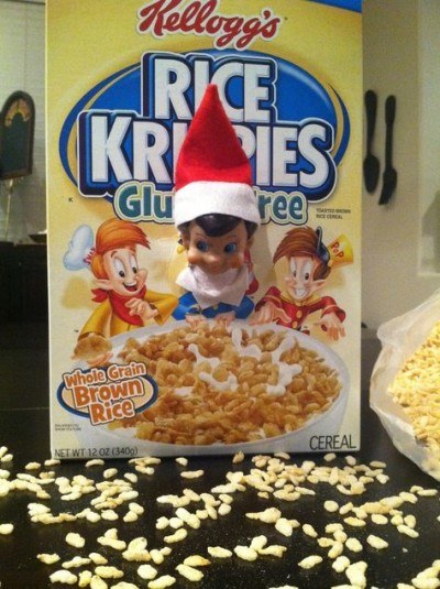 baby elf on the shelf poking head through cereal box