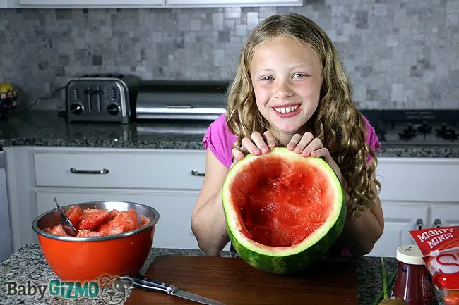 girl showing the inside of a carved out watermelon