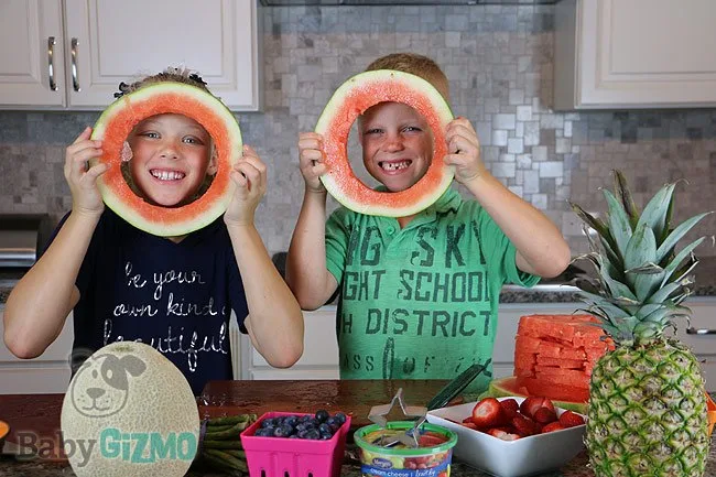 two kids looking through watermelon circles