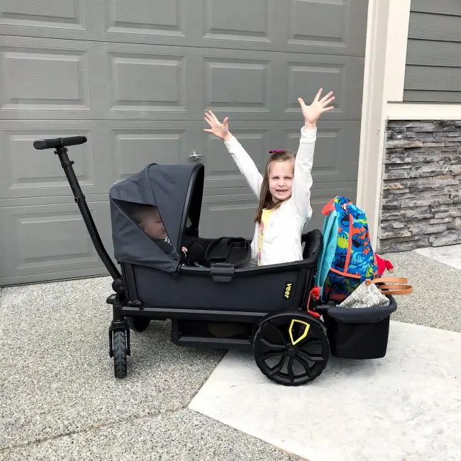 little girl with arms up in wagon