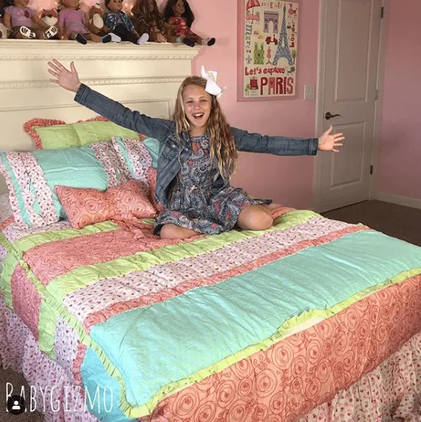 young girl on beddys covered bed