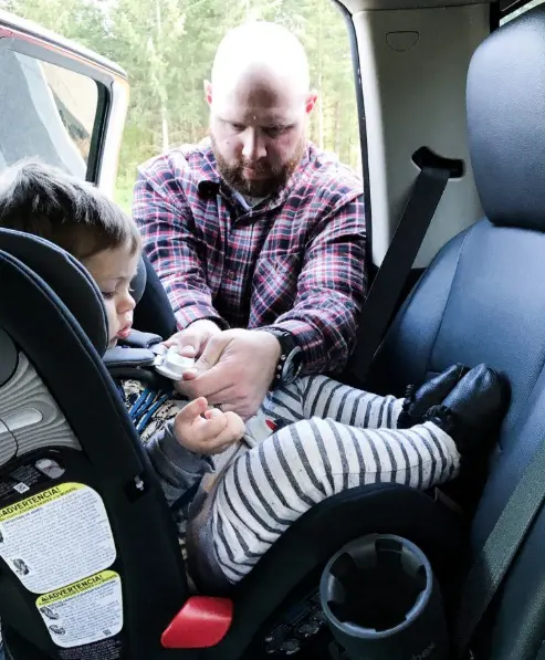 dad buckling child into car seat