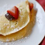 crepes with strawberry and nutella on white plate