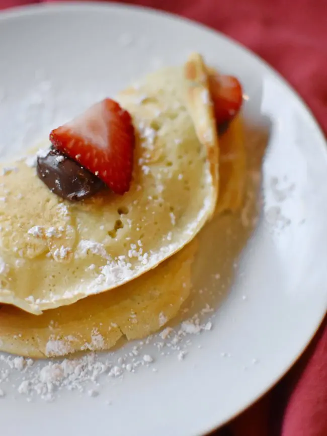 crepes with strawberry and nutella on white plate