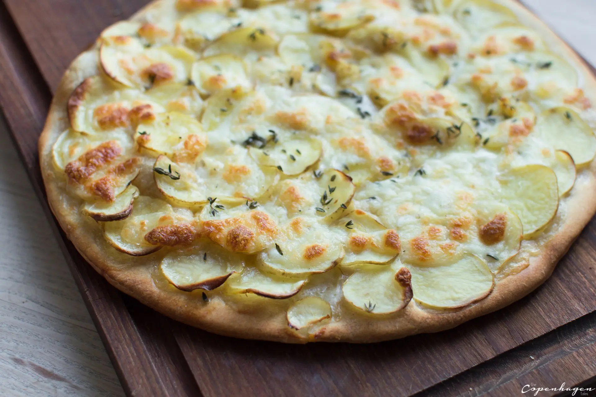 full potato pizza on cutting board not cut