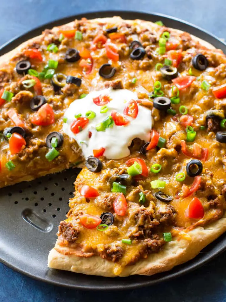 taco pizza on pizza pan with one slice removed