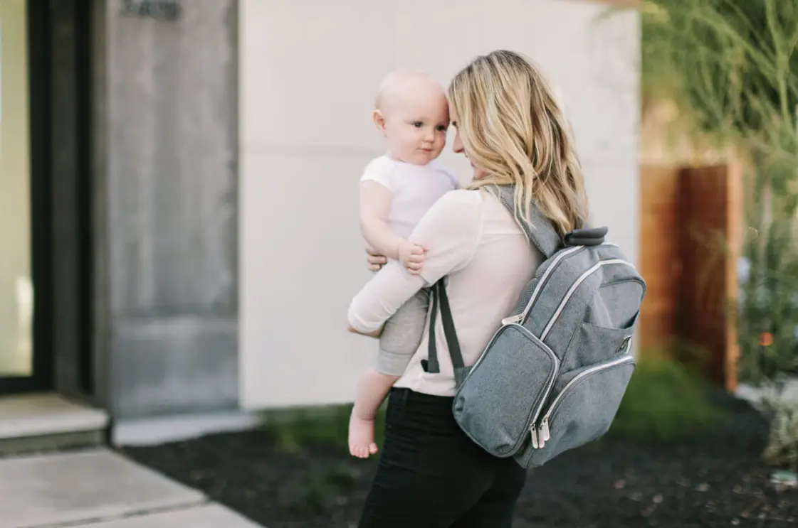 mom holding baby with grey backpack
