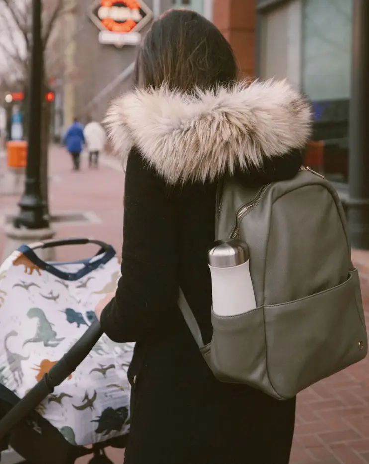 mom wearing diaper bag backpack pushing stroller