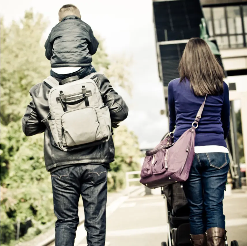 mom and dad and toddler walking with bags