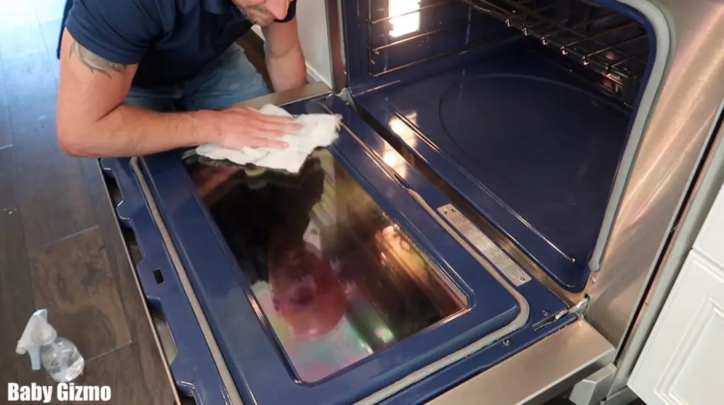 wiping down the door of an oven