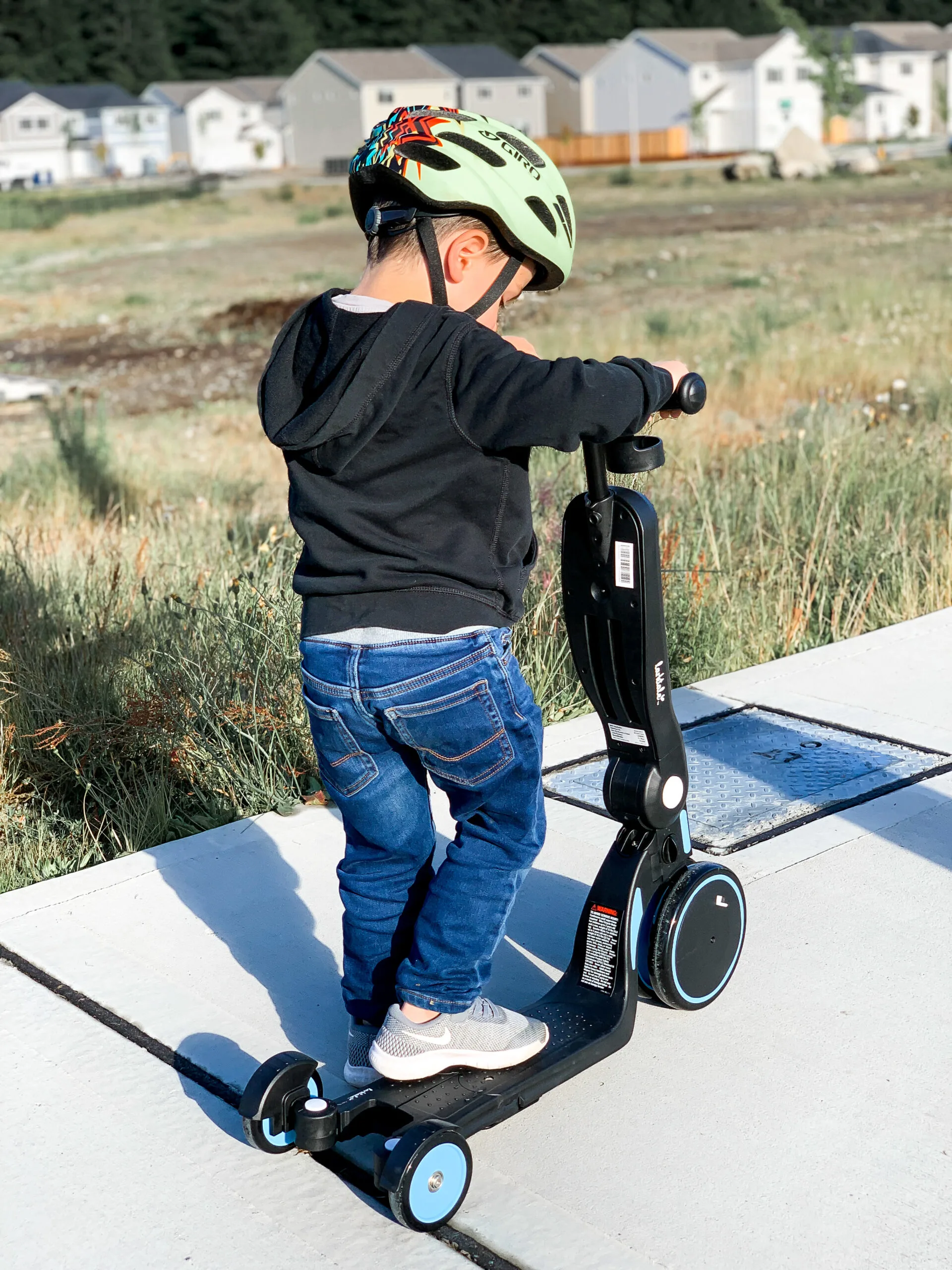 Little boy on a scooter riding down the sidewalk