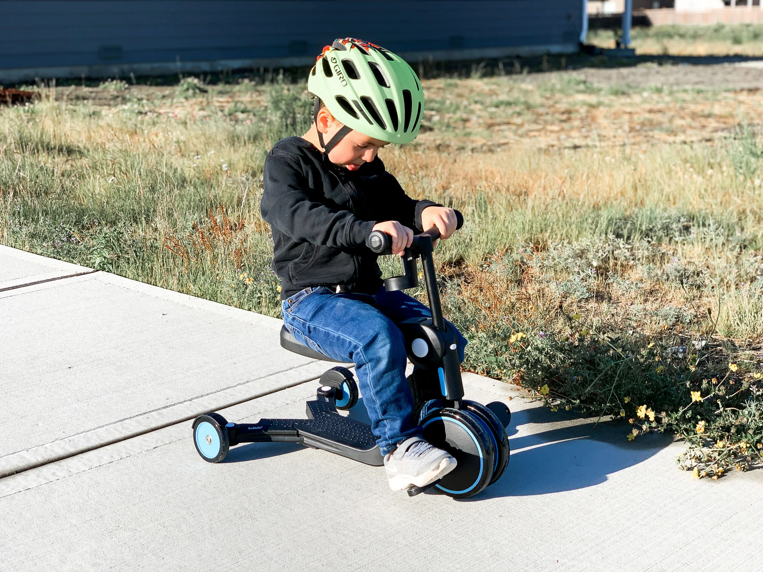 little boy riding a tricycle with a green helmet