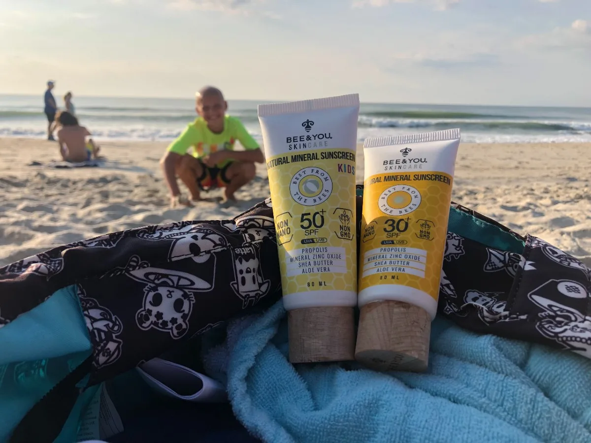 two bottles of sunscreen with boy in the background