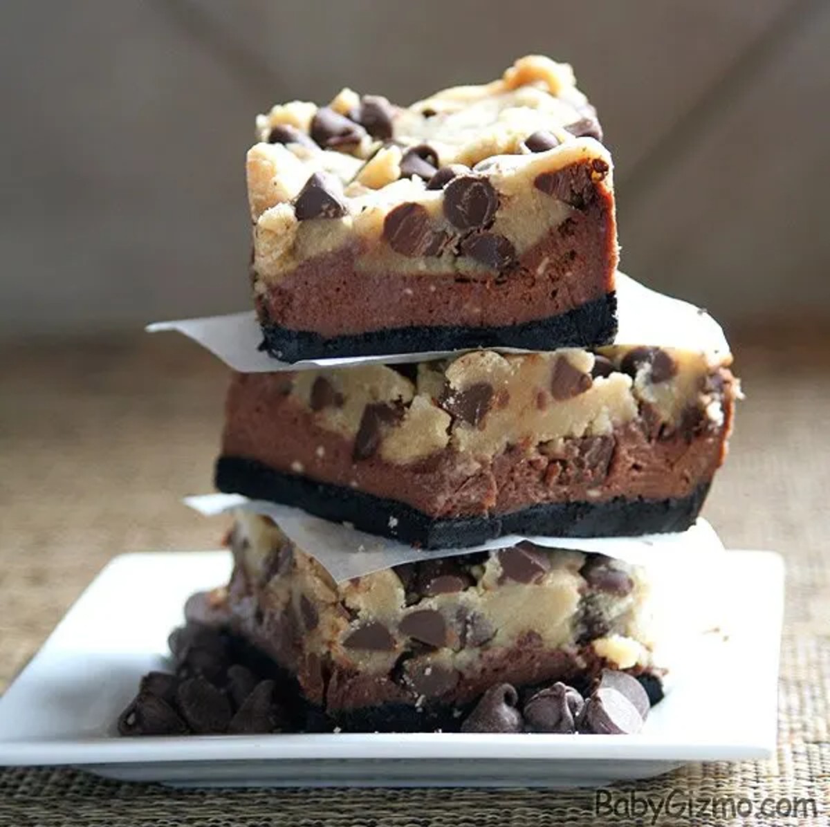 3 Chocolate Chip Chocolate Cheesecake Bars stacked on top of each other on a white plate 