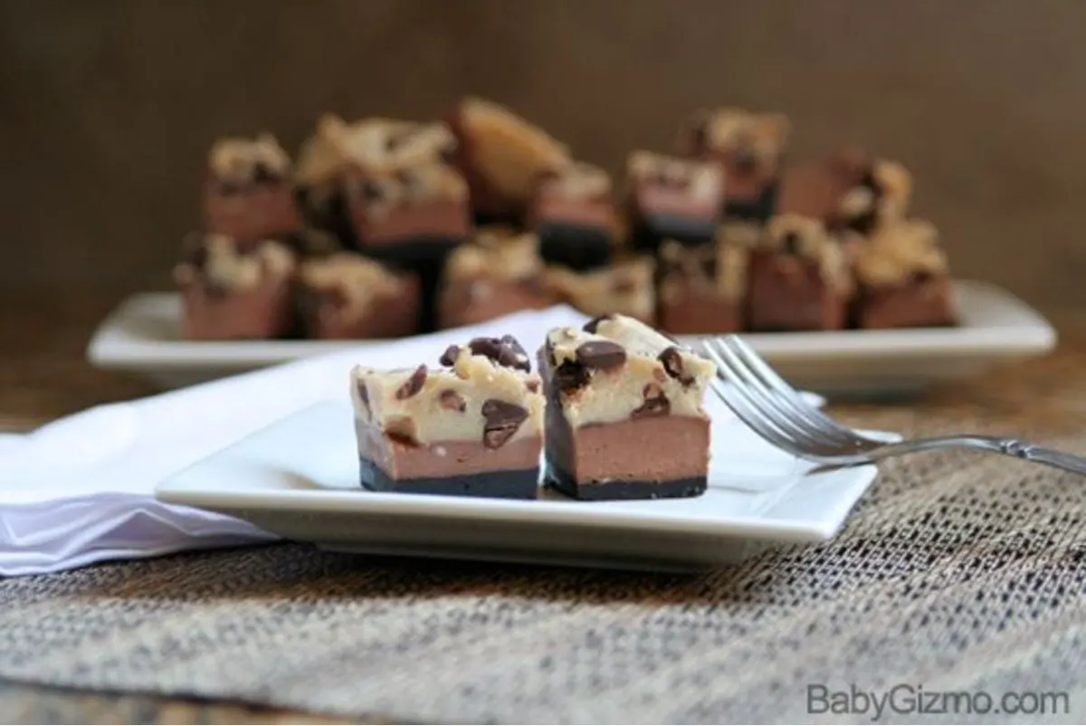 2 chocolate cheesecake cookie bits on a glass white plate with a fork on the right side 