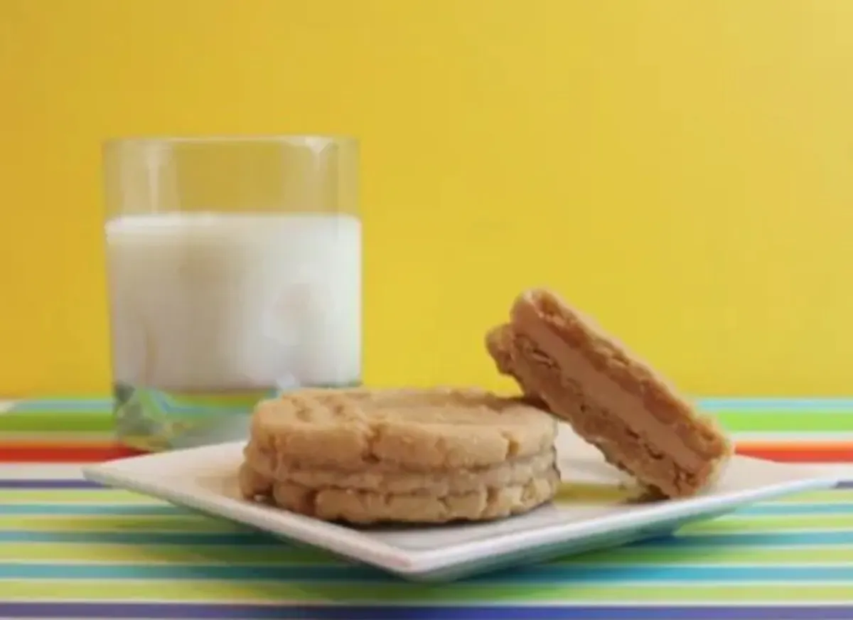 2 homemade nutter butter cookies with milk in the background