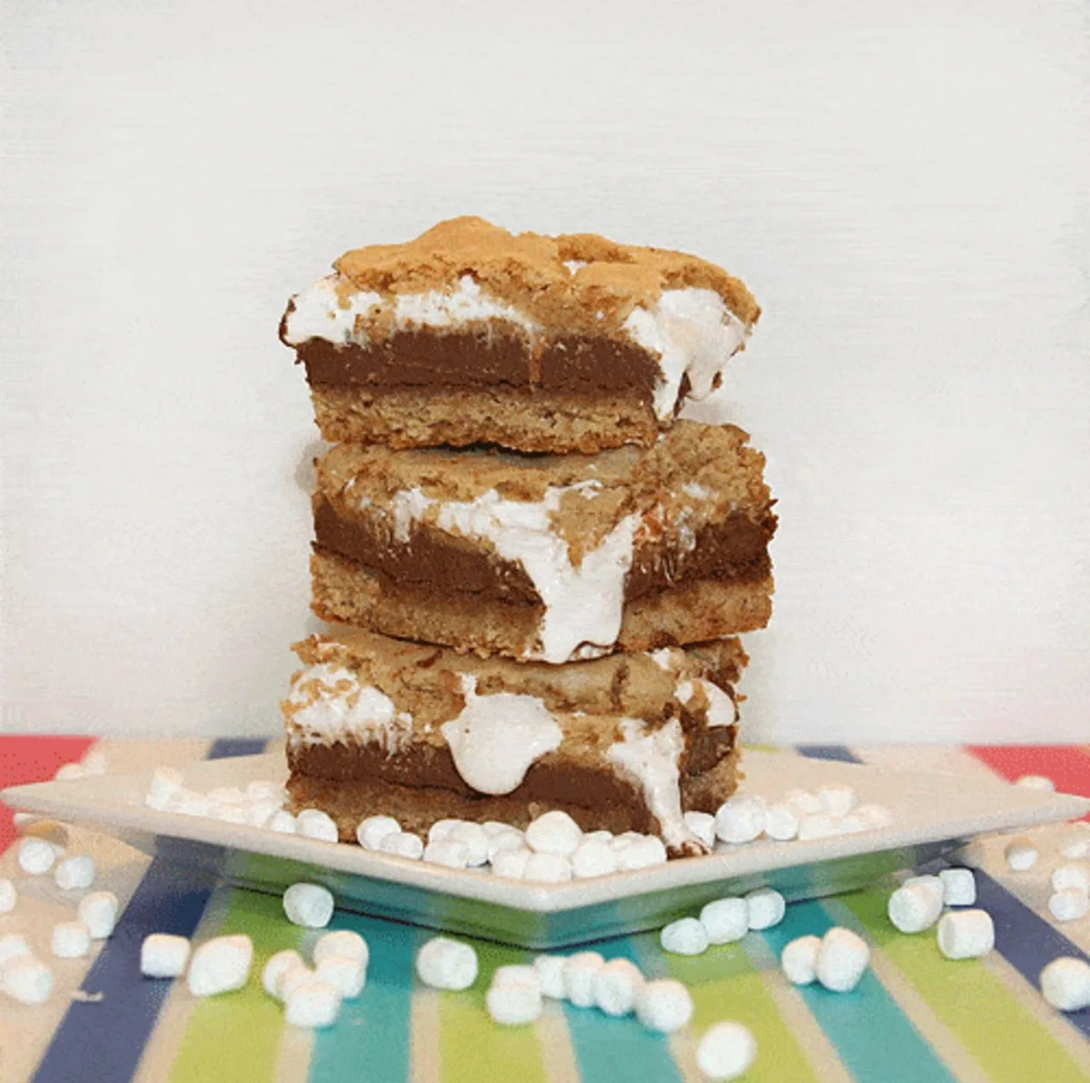 3 peanut butter s'mores bars stacked on top of each other with marshmallows on the plate 