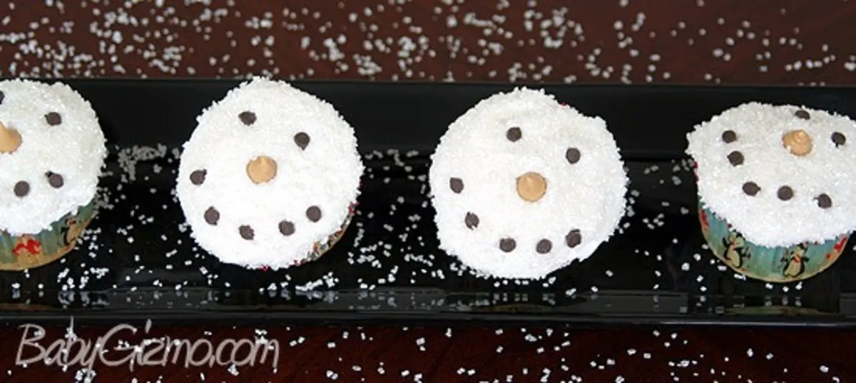 4 snowman cupcakes on a black plate